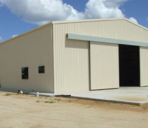 tan steel shed on concrete foundation with doors opening steel supplies