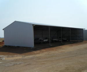 Open steel shed with vehicles parked inside steel supplies