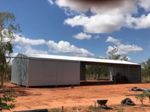 Steel shed with open walls on both sides built on red earth farm
